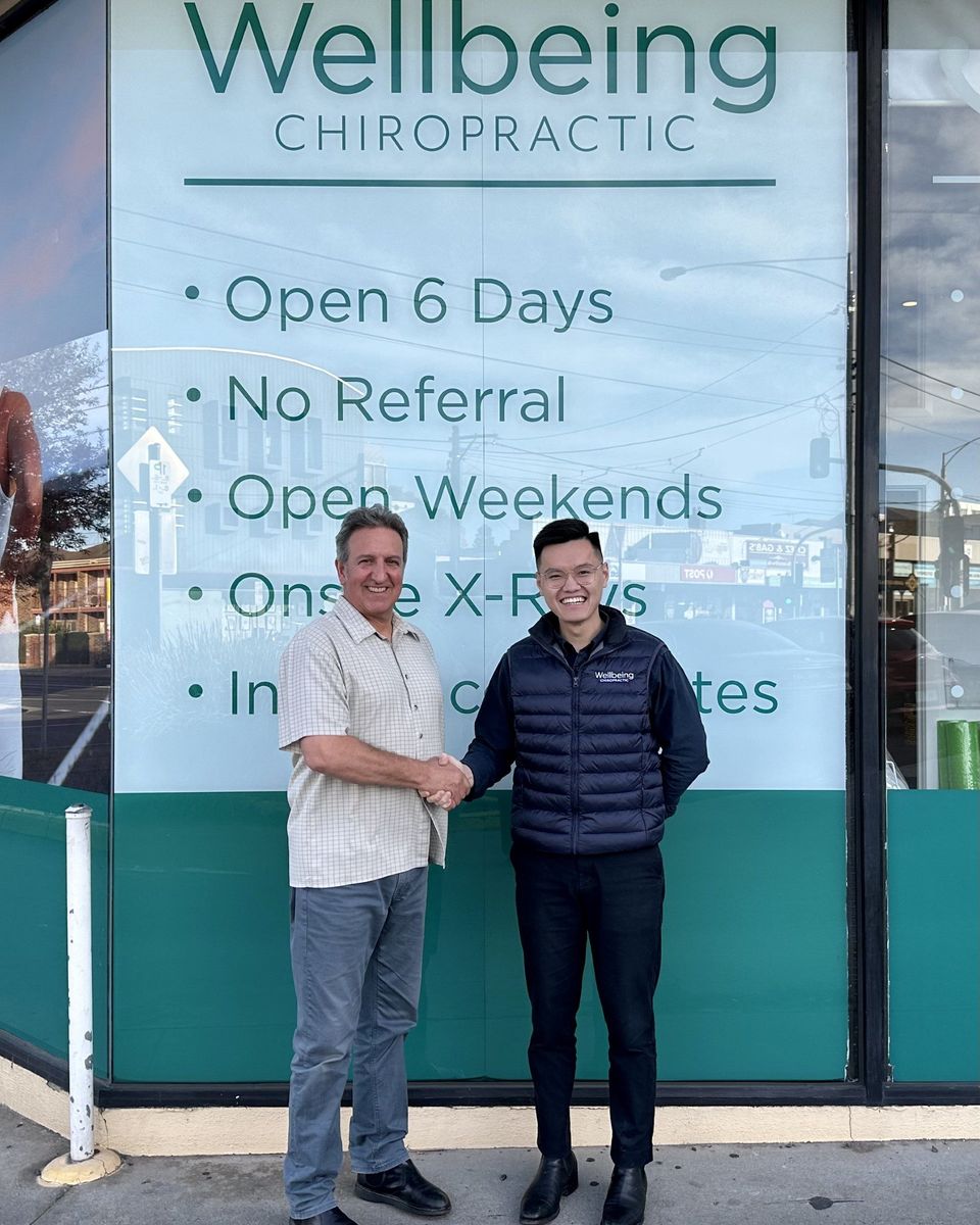Two Wellbeing Chiropractic team members shaking hands outside a clinic